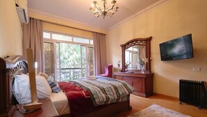 Une chambre à coucher avec un lit, une télévision, une commode, un miroir et une fenêtre.