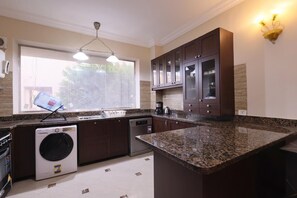Una cocina moderna con encimeras de granito, armarios de madera oscura, lavavajillas integrado y un amplio ventanal.