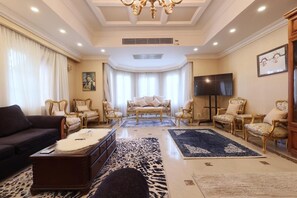 A spacious living room with a sofa, armchairs, a coffee table, and a TV. - New Cairo,vast classy 3 BR Apt.in quite villa inside fruity garden. Guarded 24/7 (New Cairo City)