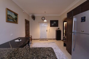 A compact kitchen with a refrigerator, a dining table, and a door leading to another room. - New Cairo,vast classy 3 BR Apt.in quite villa inside fruity garden. Guarded 24/7 (New Cairo City)