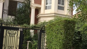 A gated entrance with a number '85' sign, a paved pathway, and a well-maintained hedge. - New Cairo,vast classy 3 BR Apt.in quite villa inside fruity garden. Guarded 24/7 (New Cairo City)