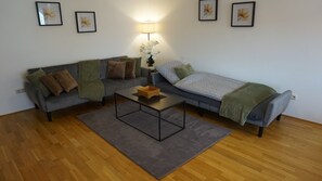 Ein Wohnzimmer mit einer Couch, einem kleinen Sofa, einem Couchtisch und einer Lampe.