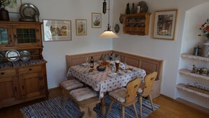 Ein Essbereich mit einem Holztisch, Stühlen, einer Bank und einer Tischdecke mit Muster.
