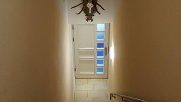 Eine Treppe mit hölzernem Geländer, ein an der Wand befestigter Hirschschädel und eine Tür mit satinierten Glasfeldern.