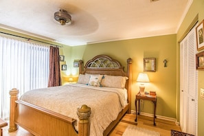 Ein Schlafzimmer mit einem hölzernen Bett, einem Nachttisch mit Lampe, einem Deckenventilator und einem Wandspiegel.