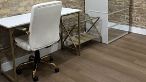 Una habitación con un escritorio blanco, una silla blanca, un armario blanco y una pared de piedra.