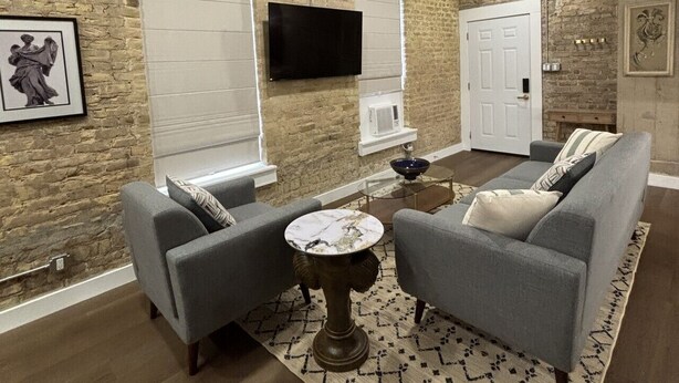 Una sala de estar con chimenea, un televisor de pantalla plana en la pared y un sofá con cojines.