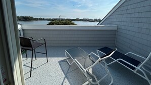 Un balcón con vistas al agua, una silla y una mesa.