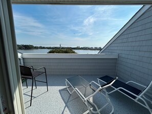 Ein Balkon mit Blick auf ein Gewässer, einem Stuhl und einem Tisch.