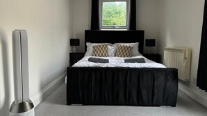 Una camera da letto con un letto grande, due comodini, una finestra, un termosifone e un riscaldatore.