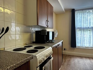 Una cocina con estufa, microondas y armarios.