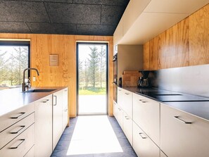 Eine moderne Küche mit Holdekor, einer schwarzen Arbeitsplatte und Blick auf Bäume.