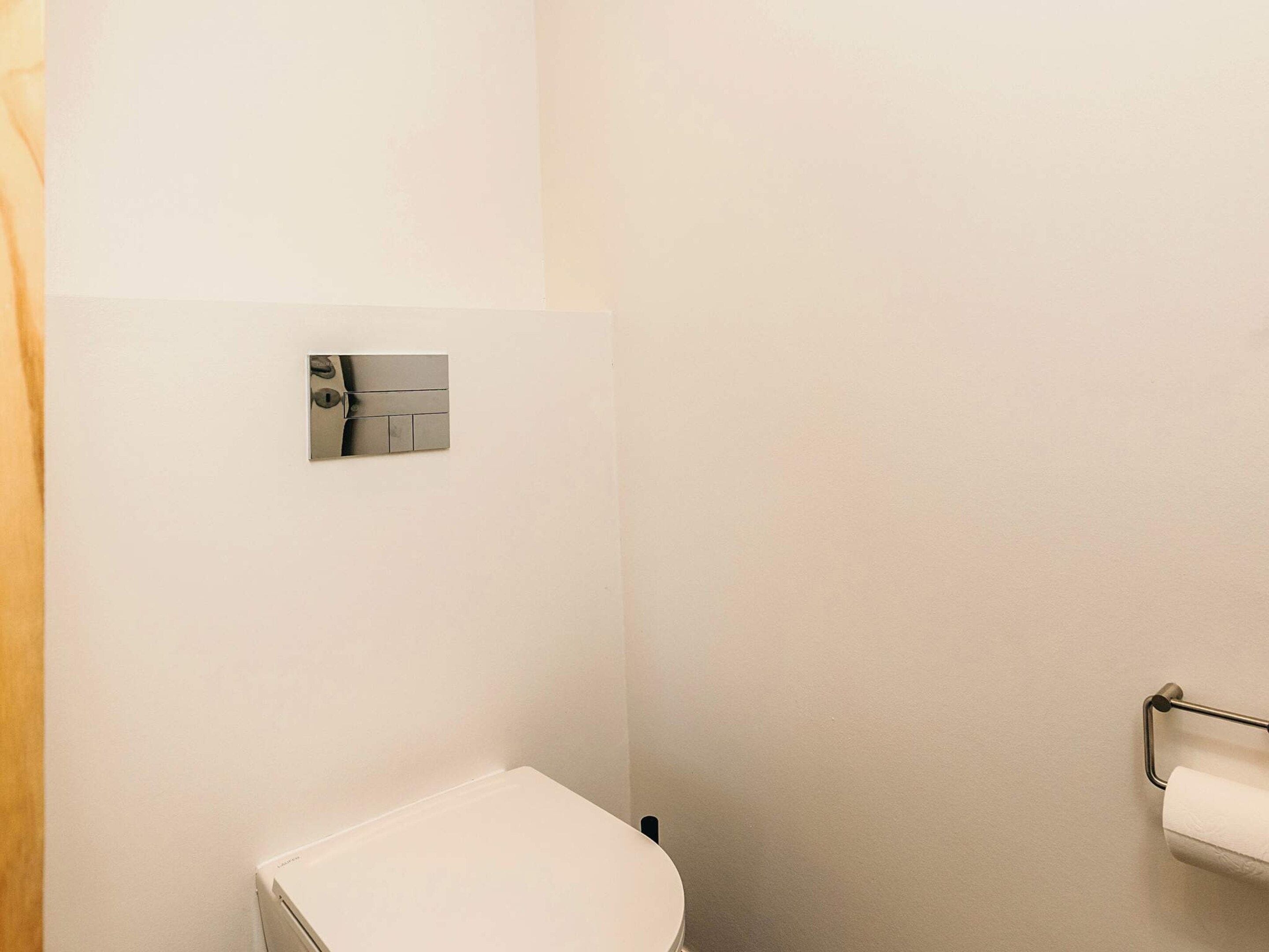 A small, white bathroom with a toilet, a towel rack, and a mirror.