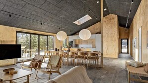 A spacious living area with a large TV, wooden furniture, and a kitchen in the background. - 5 Star Holiday Home in Saeby (Sæby)
