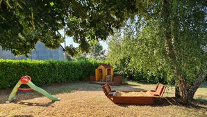 A playground with a slide, swings, and a small playhouse.