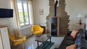 A living room with a fireplace, a sofa, a yellow armchair, a TV, and a radiator.