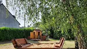 A wooden deck with a bench and a small wooden structure in a garden.