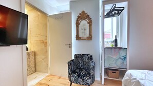 A bedroom with a bed, a TV, a chair, a door, and a window with a view. - AZZULEA Rossio Suite 2 (Lisboa)