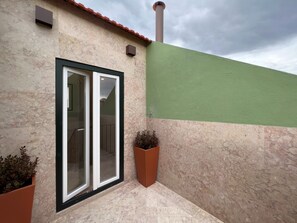 A building with a green wall, a tiled floor, and a window with a black frame. - AZZULEA Rossio Suite 2 (Lisboa)