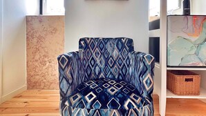 A chair with a geometric pattern, a mirror with an ornate frame, and a wall with a textured finish. - AZZULEA Rossio Suite 2 (Lisboa)
