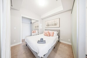A bedroom with a bed, a mirror, and a painting on the wall. - Upscale 3BR/2BA | Cold Plunge · Sauna · Steam | Parking | Downtown Toronto (Toronto)