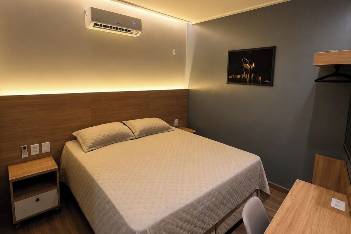 Una habitación de hotel con cama, mesita de noche y escritorio con silla.