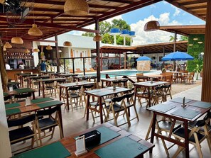 An outdoor dining area with tables and chairs, a pool, and umbrellas. - Araguari Hotel Ferreira Gomes  (Ferreira Gomes)