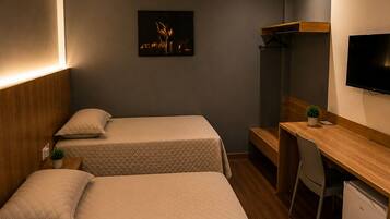 Een hotelkamer met twee bedden, een bureau, een televisie en een kleine koelkast.