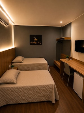 A hotel room with two beds, a desk, a TV, and a small refrigerator. - Araguari Hotel Ferreira Gomes  (Ferreira Gomes)