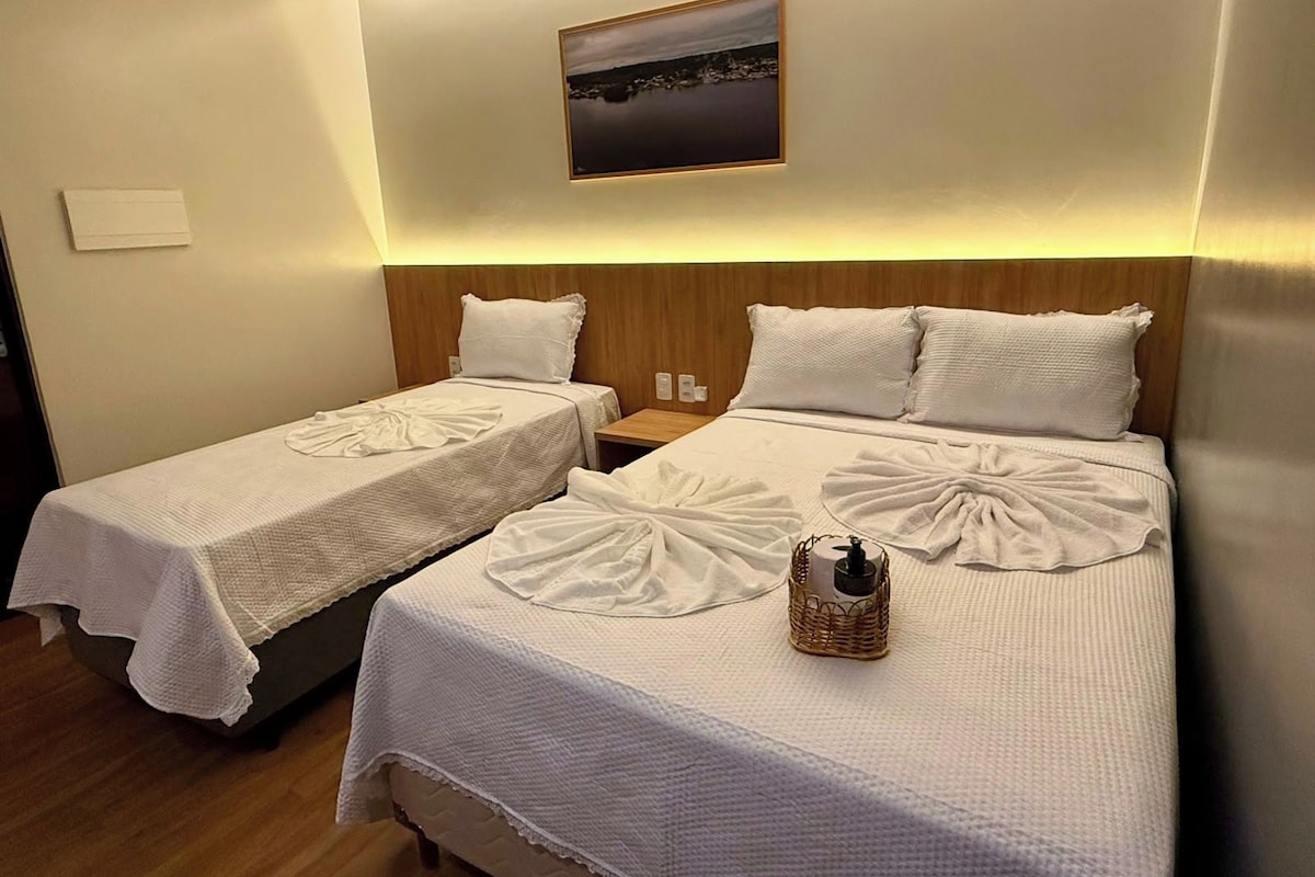 A hotel room with two beds, each with a neatly folded white towel and a small wicker basket.