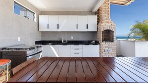 A kitchen with white cabinets, a gas stove, and a brick oven. - Altos do Caju - Triplex in Pirangi 300 Meters From the World's Largest Cashew Tree by Carpediem (Parnamirim)