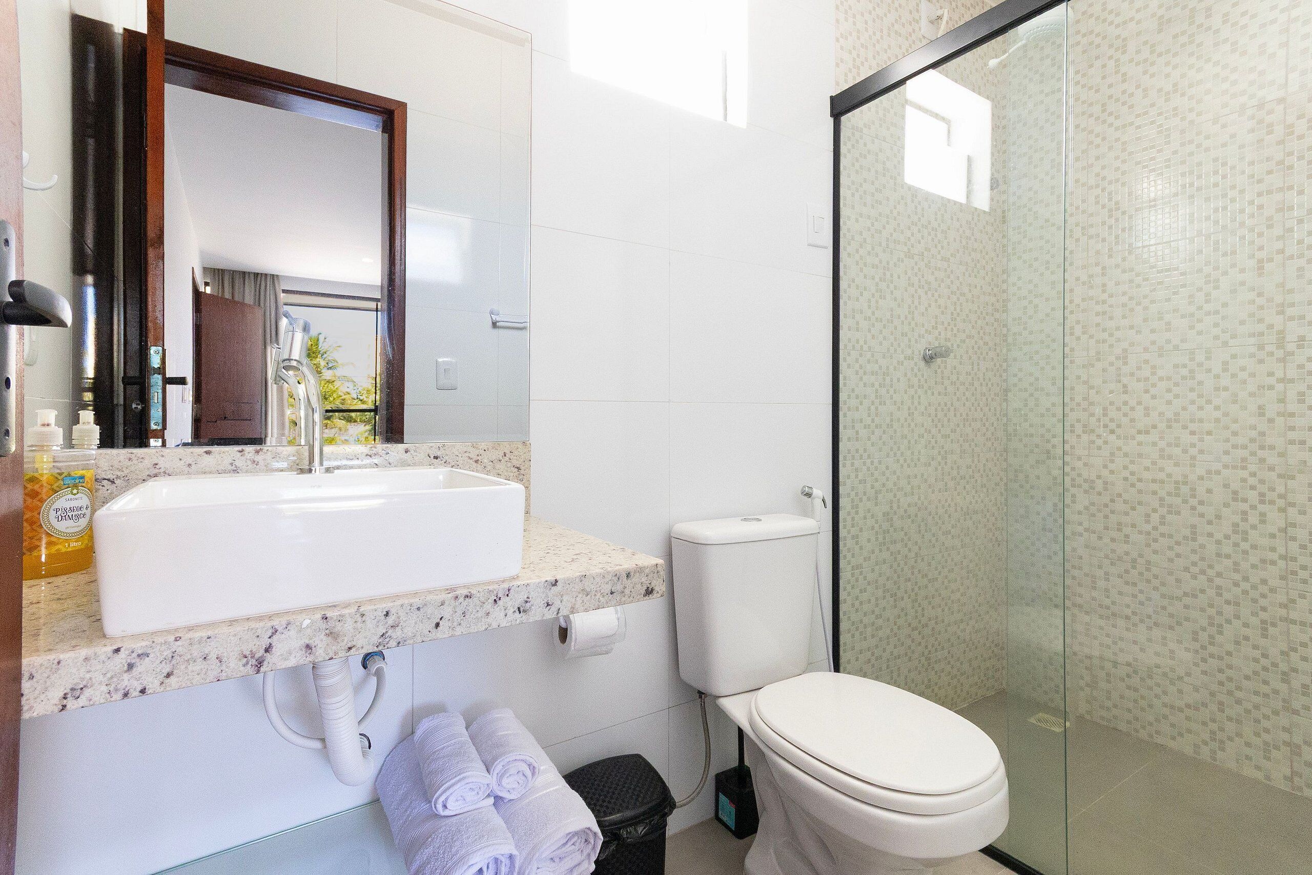 Een badkamer met een wastafel, toilet en douchecabine met glazen wanden.