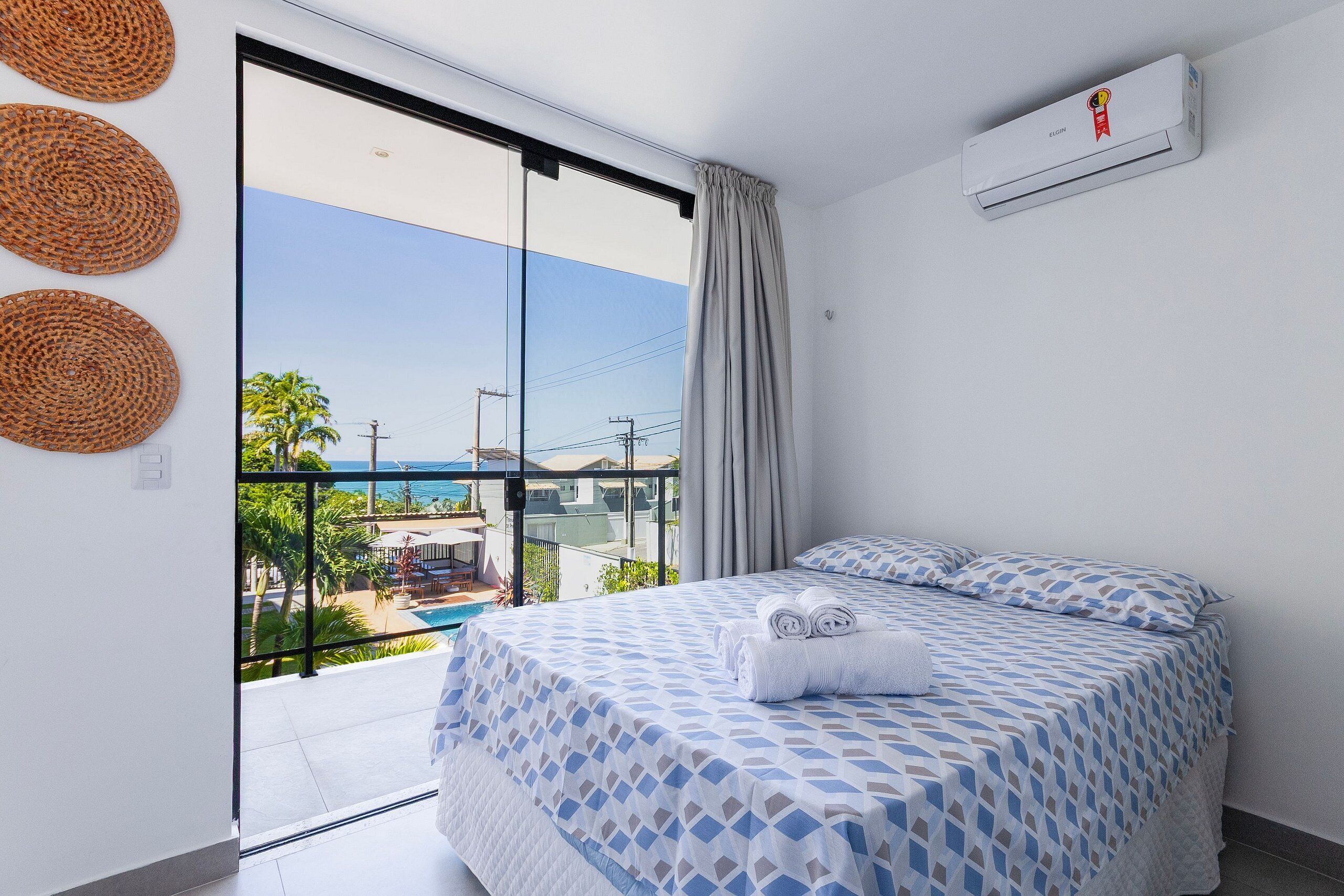 A bedroom with a bed, a window, and a view of a pool and palm trees.