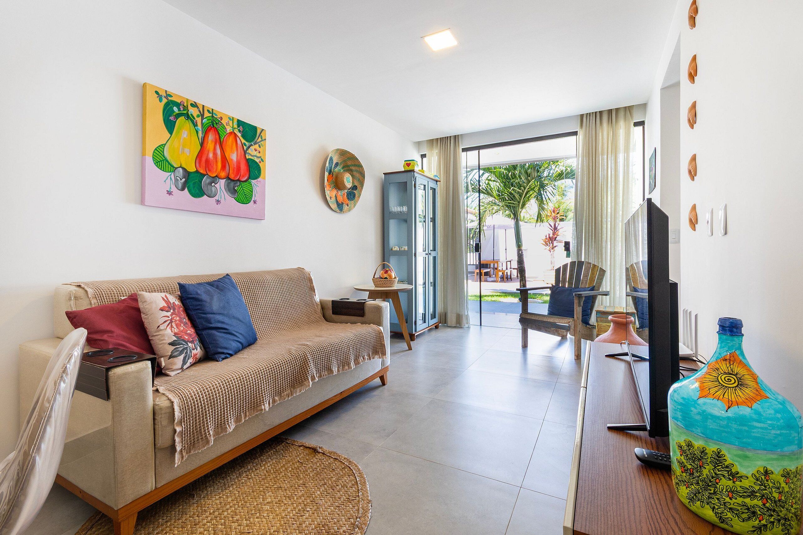 A living room with a sofa, TV, and artwork.