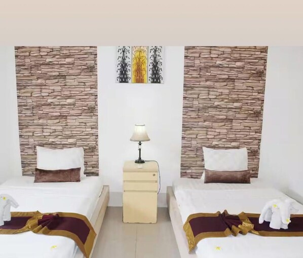 A hotel room with two beds, a nightstand with a lamp, and a wall art piece above the beds. - CJs House Gili Trawangan (Gili Trawangan)