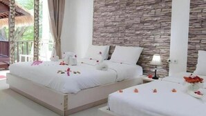 A hotel room with two beds, a stone wall, a window with curtains, and a nightstand with a lamp. - CJs House Gili Trawangan (Gili Trawangan)