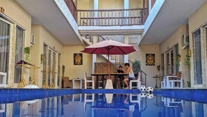 A swimming pool with a reflection, a covered seating area, and a staircase leading to an upper level. - CJs House Gili Trawangan (Gili Trawangan)
