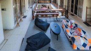 A spacious indoor area with a long bench, a sofa, and two black poufs. - CJs House Gili Trawangan (Gili Trawangan)