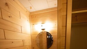 A wooden-paneled bathroom with a sink, mirror, and light fixture.