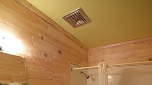 A bathroom with wooden panel walls, a white sink, toilet, and bathtub with a shower curtain.