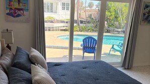A bedroom with a large bed, a view of a swimming pool, and a balcony. - Siesta Key Village Home (Siesta Key)