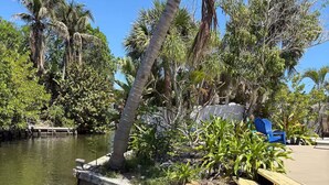 A wooden dock extending into a calm body of water, surrounded by lush greenery and palm trees. - Siesta Key Village Home (Siesta Key)