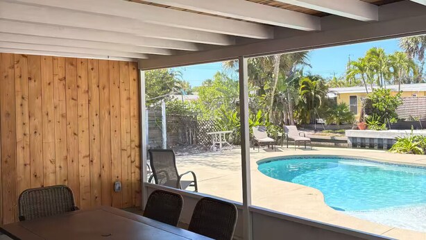An enclosed patio with a pool, wooden ceiling, and a table with chairs. - Siesta Key Village Home (Siesta Key)