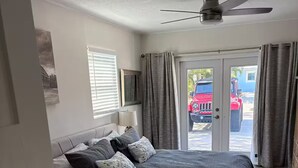 A bedroom with a bed, a ceiling fan, a window with blinds, and a door leading outside. - Siesta Key Village Home (Siesta Key)