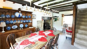 Un comedor rústico con una mesa de madera, sillas y una pared decorada con platos azules y blancos.