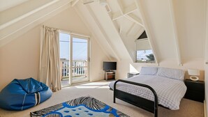 Una camera da letto con un letto, una televisione, una scrivania, una sedia e un balcone.
