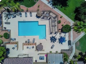An aerial view of a swimming pool area with lounge chairs, a sunbed, and a covered seating area. - Cozy 1-bed A/C condo in beautiful Phoenix with Pool, Golf Simulator and Gated (Phoenix)