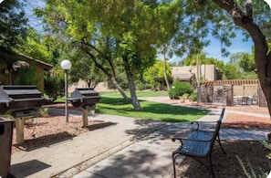 An outdoor patio area with barbecue grills, a bench, and a street lamp. - Cozy 1-bed A/C condo in beautiful Phoenix with Pool, Golf Simulator and Gated (Phoenix)