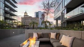 Une terrasse sur le toit, agrémentée d’un foyer, d’un canapé et offrant une vue sur un bâtiment historique.