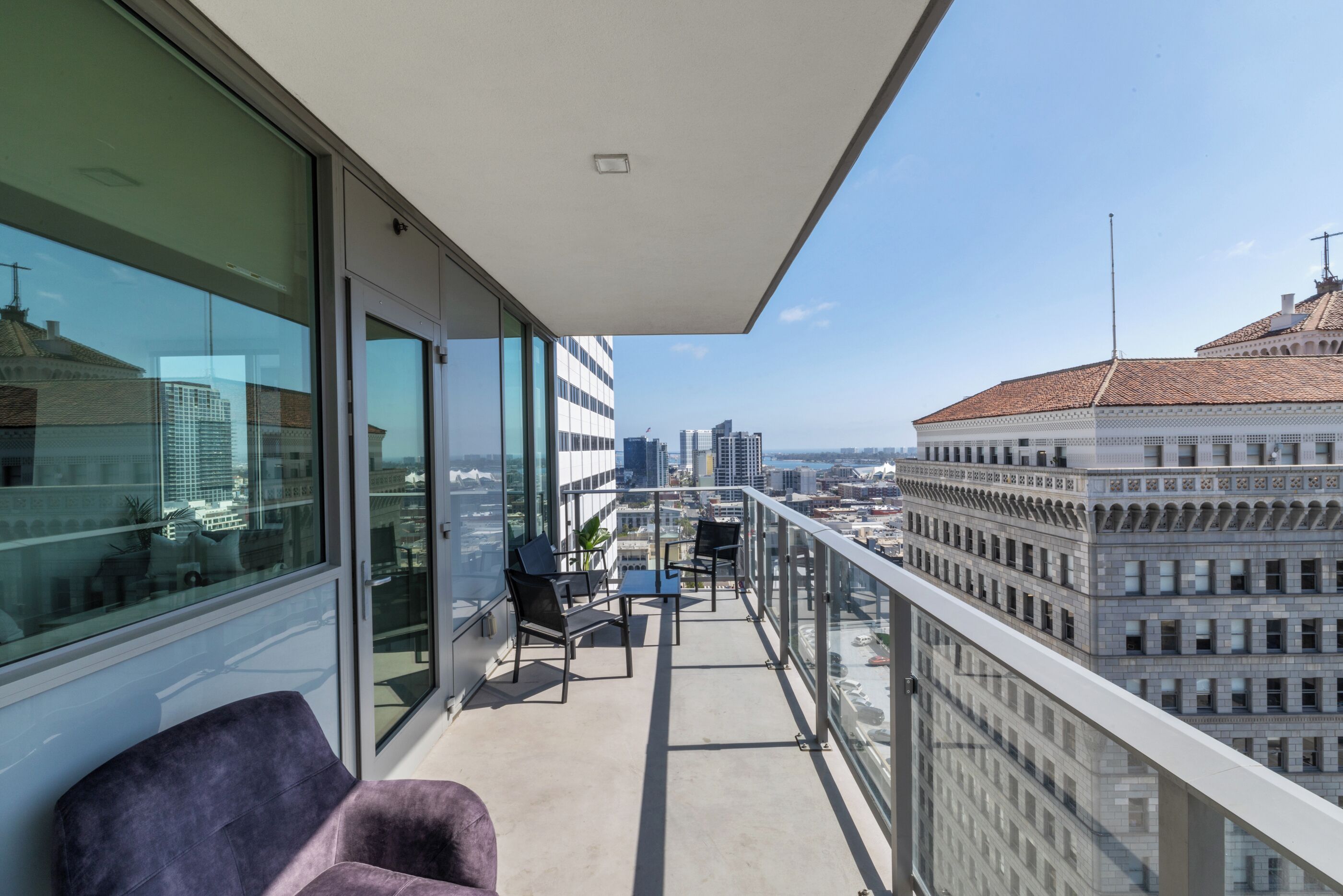 Een balkon met uitzicht op de stad, moderne meubels en een glazen deur.